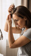 © D-point - Woman checking her hair in mirror, inspecting scalp for hair loss. Female observing new hair growth. Healthy hair concept.