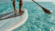 © Ananda - Person paddleboarding on clear turquoise ocean water with sunlight