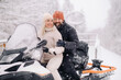 © Alex - A couple, a man and a woman, on a snowmobile in a winter forest