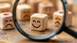 © Stock by Hemal - A single wooden block with a smiling face stands out among sad ones under a magnifying glass. Concept for positive attitude or finding talent in business.