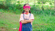 © Thawatchai Images - Portrait of happy young Asian girl wearing pink superhero cape and eye mask standing with arms crossed in park, smiling confident brave kid, leadership and girl power concept.