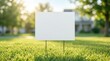 © Masque - A white blank sign for outdoor advertising stands in a lush grassy field.