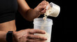 © umang - Athletic Woman Adding Scoop of Protein Powder to Shaker Bottle