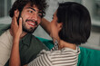 © Zamrznuti tonovi - Happy young couple smiling and laughing, female partner touching man's face, showing romantic connection at home