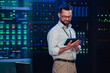 © Zamrznuti tonovi - It engineer monitoring data center servers, checking network infrastructure performance with a tablet computer