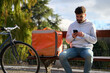 © Oscar - Courier checking smartphone while resting during delivery job