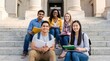 © AspctStyle - Multiracial group of college students sitting on university steps with notebooks. Diverse international classmates on campus for education recruitment.