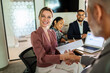 © Marko Geber - Smiling businesswoman shaking hands in modern office meeting