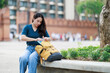 © Tj - Young asian woman traveler getting book from backpack, preparing for city tour, exploring ancient architecture and cultural heritage in Chiang Mai, Thailand