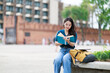 © Tj - Student learning and reading a book outdoors, sitting and studying at Tha Phae Gate in Chiang Mai, a female tourist enjoying education and knowledge