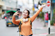 © Tj - Young Asian woman traveler posing for a smartphone selfie video. Enjoying city exploration. Documenting her journey and sharing moments of happiness online