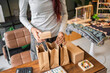 © Charlie's - Woman packing customer purchase into paper bag for small business with sustainable packaging and eco friendly retail Green business.