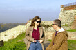 © tanyatorgonskaya - Woman in autumn coat listens attentively to man beside ancient fortress walls. Symbolizes active listening, meaningful dialogue, conversational presence, and respectful interpersonal communication.