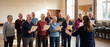 © Yana - Senior choir singing together with a conductor in a community hall. Music hobby, social connection, friendship and joyful retirement.