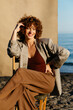 © Tania Cervian/Stocksy - Woman with curly hair smiling sitting on beach chair