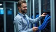 © Viktor - Smiling male technician connects blue network cables in professional server room. Bearded specialist works with rack hardware maintenance in data center. Infrastructure manager performs routine
