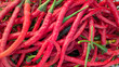 © Maule - Close up background of fresh long red curly chili peppers with green stems, ideal for cooking, food, and culinary concept.