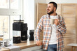 © Pixel-Shot - Young man with cup and coffee machine in kitchen