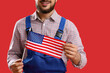 © Pixel-Shot - Male worker with USA flag on red background, closeup. Labor Day celebration
