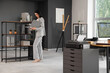 © Pixel-Shot - Young woman with folder near shelving unit in stylish office