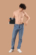 © Pixel-Shot - Handsome young happy sporty man in loose jeans with scales on brown background. Weight loss concept