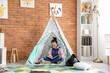 © Pixel-Shot - Cute little girl reading adventure book in play tent at home