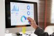 © Matawut - Business professional analyzing company performance on a computer display, examining financial graphs and charts for data analytics, market research, and strategic reporting