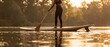 © itlada - Woman paddleboarding on a calm lake at sunset, enjoying a serene moment of outdoor recreation and fitness with golden light reflecting on the water for commercial technology, business
