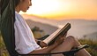 © EBG Stock Studio - Mujer joven leyendo en una tableta mientras descansa al aire libre frente a un paisaje iluminado por la luz cálida del atardecer