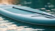 © The Little Hut - Close-up of a Stand Up Paddleboard with Paddle Resting on Water Surface