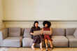 © BONNINSTUDIO/Stocksy - Businesswomen collaborating remotely on laptops on a sofa