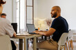 © BONNINSTUDIO/Stocksy - Man typing at laptop during meeting at bright office