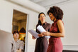 © BONNINSTUDIO/Stocksy - Professionals discussing documents during a business meeting