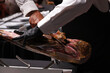 © planeta11 - maestro jamonero manipulando un jamón ibérico para limpiarlo de su costra