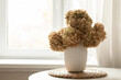 © svetlana_cherruty - Dried hydrangea bouquet in white ceramic vase on bright window sill cozy autumn home decor