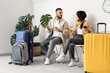 © Pixel-Shot - Worried young couple with luggage waiting for their flight in airport lounge