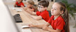 © Pixel-Shot - Young girl in red shirt using a computer mouse in a classroom with Other children learning technology, Other children are visible in the background, also engaged with computers