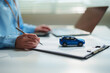 © Joi_studio - Close-up customer signing a car insurance or vehicle financing agreement beside a model SUV, auto insurance, vehicle ownership, loan approval, leasing, and financial protection