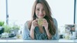 © Surachetsh - A joyful young Asian woman lounges comfortably on a cozy morning, smiling as she sips a warm cup of coffee or tea and lets herself drift into a daydream.