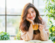 © Surachetsh - A joyful young Asian woman lounges comfortably on a cozy morning, smiling as she sips a warm cup of coffee or tea and lets herself drift into a daydream.