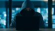 © Yassine - Anonymous hooded hacker at laptop in dark office, cyber criminal committing data breach, mysterious man in mask and hoodie
