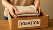 © AnastasiiaAkh - Volunteer packing donated clothing into charity donation box for community support