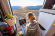 © mrzn - Woman working on laptop inside camper van during golden hour with mountain adventure lifestyle technology computer