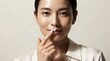 © SnapSpark Studios - Young asian woman applying moisturizing cream on her lips for skincare routine portrait