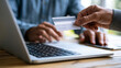 © Anastasiia Havelia - Detailed close-up photographic stock image focusing on a person's hands performing a digital transaction. One hand holds a minimalist matte white payment card above a modern silver