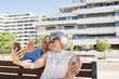 © Almu Zambrana/Stocksy - Senior couple waving on video call outside luxury apartments