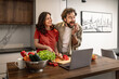 © ivanko80 - Happy couple cooking a healthy meal together in a modern kitchen while following an online recipe