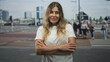 © Krakenimages.com - Middle age woman with crossed arms at a busy street crosswalk, wearing white t shirt and neutral expression; confidence resilience.