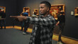 © Krakenimages.com - Young black man in plaid shirt pointing index finger toward framed painting in museum gallery hall; curiosity focus engagement.
