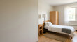 © Вадим Перегудов - Simple student dorm room interior with a single bed and wooden furniture. Minimalist college accommodation with desk and wardrobe. Bright residential space